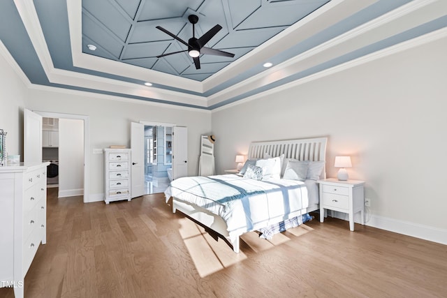 bedroom featuring crown molding, a raised ceiling, a ceiling fan, wood finished floors, and baseboards