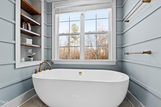 bathroom featuring a soaking tub and baseboards