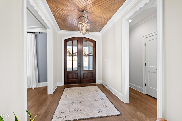 foyer with dark wood-type flooring, french doors, wooden ceiling, and ornamental molding