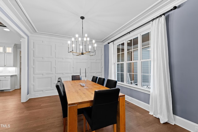 dining space with ornamental molding, an inviting chandelier, baseboards, and wood finished floors