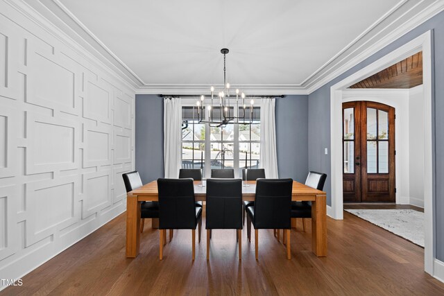 dining space with ornamental molding, french doors, dark wood-type flooring, and a notable chandelier