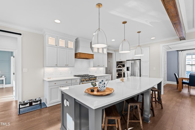 kitchen featuring a spacious island, custom range hood, appliances with stainless steel finishes, dark wood-style flooring, and backsplash