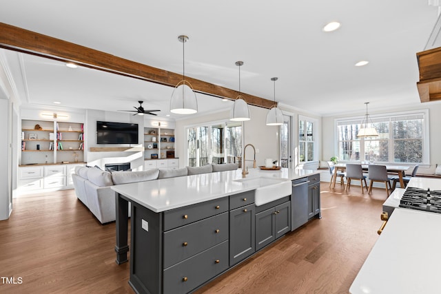 kitchen featuring beam ceiling, crown molding, light countertops, a sink, and dishwasher