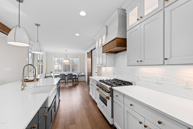 kitchen featuring tasteful backsplash, custom exhaust hood, light countertops, a sink, and gas stove