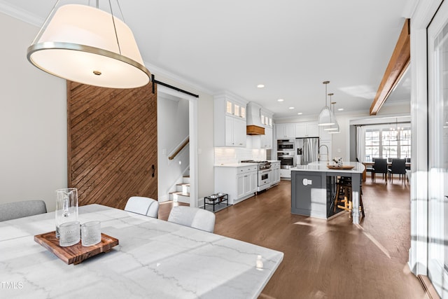 dining area featuring a barn door, ornamental molding, dark wood-type flooring, stairs, and recessed lighting