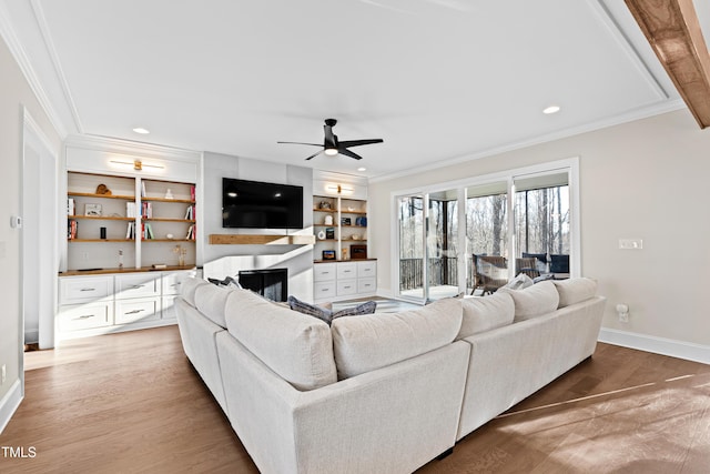 living room featuring baseboards, ceiling fan, ornamental molding, light wood-style floors, and a fireplace