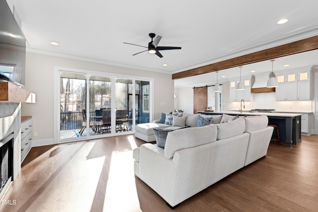 living area featuring ceiling fan, wood finished floors, crown molding, and a barn door