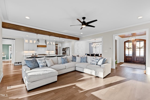 living area with recessed lighting, french doors, crown molding, and wood finished floors