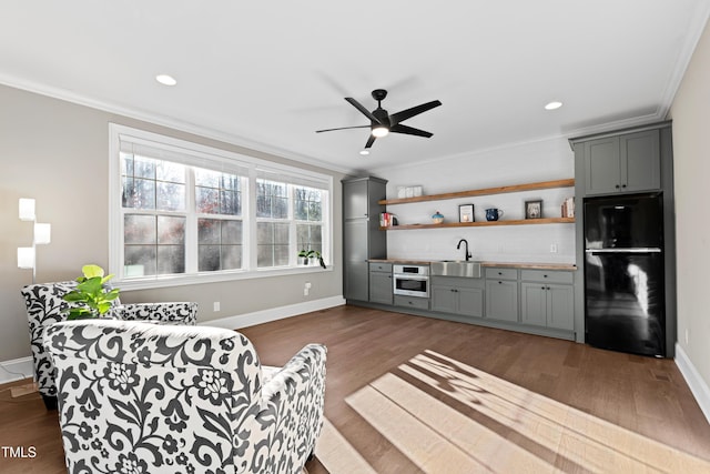 living area with a ceiling fan, baseboards, dark wood-style flooring, and crown molding