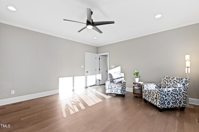 sitting room with crown molding, visible vents, ceiling fan, wood finished floors, and baseboards