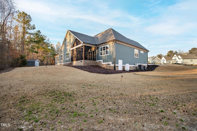 exterior space with an outbuilding, a sunroom, crawl space, central AC, and a shed