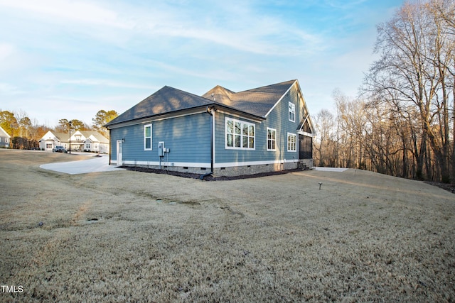 view of side of home with driveway, crawl space, and a lawn