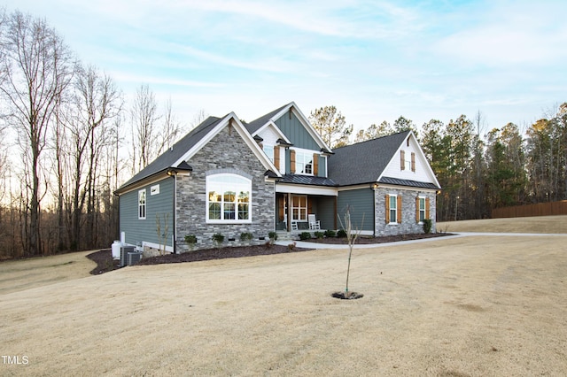 view of front of house featuring a standing seam roof, stone siding, metal roof, and board and batten siding