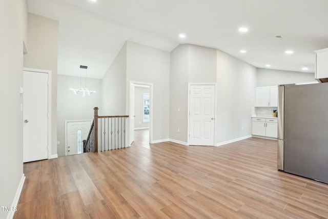 interior space featuring baseboards, high vaulted ceiling, recessed lighting, light wood-style floors, and a chandelier