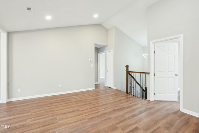 empty room featuring baseboards, lofted ceiling, visible vents, and light wood finished floors