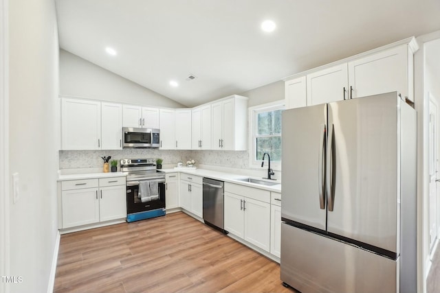 kitchen featuring tasteful backsplash, light wood-style flooring, appliances with stainless steel finishes, white cabinetry, and a sink