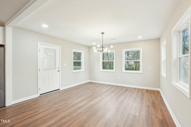 empty room featuring a healthy amount of sunlight, light wood-type flooring, and baseboards