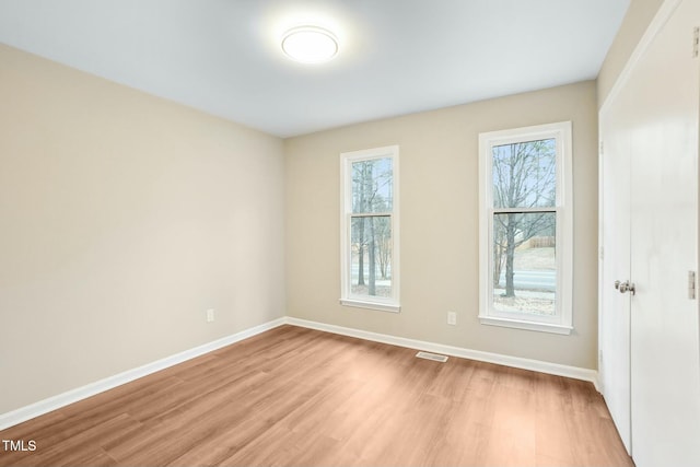 spare room featuring visible vents, light wood-style flooring, and baseboards