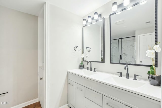 full bath featuring double vanity, an enclosed shower, baseboards, and a sink