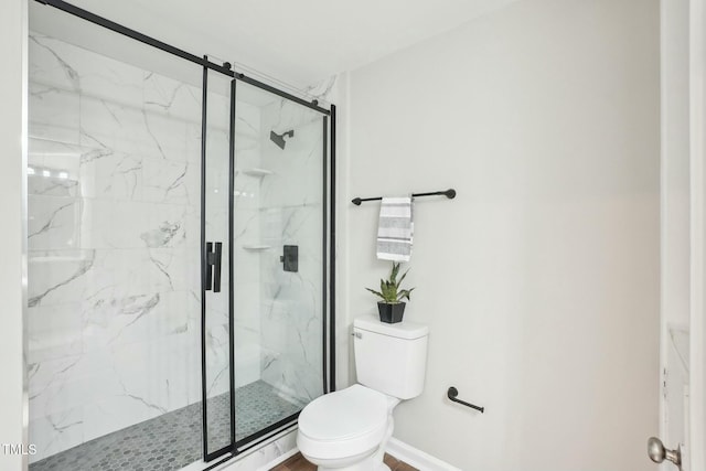 full bath with a marble finish shower, baseboards, and toilet