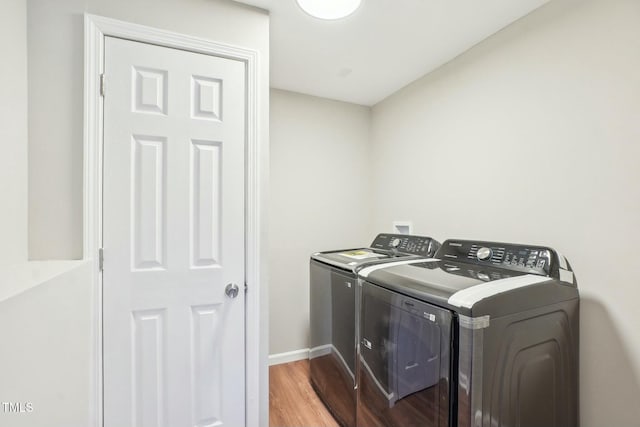 laundry room featuring baseboards, wood finished floors, washing machine and dryer, and laundry area