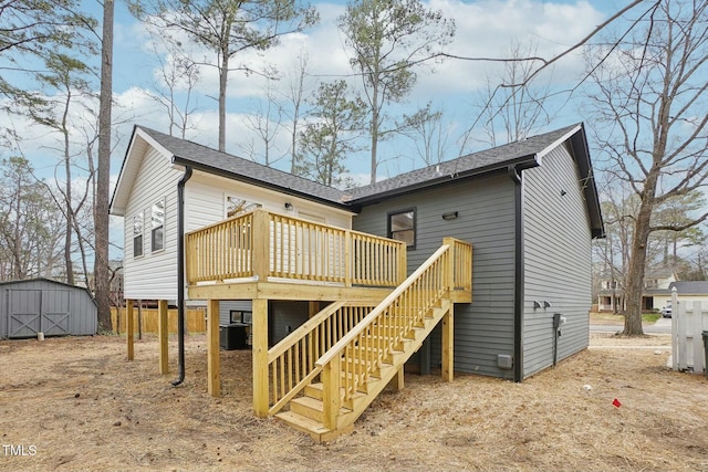 back of house featuring central air condition unit, a wooden deck, stairs, an outdoor structure, and a storage unit