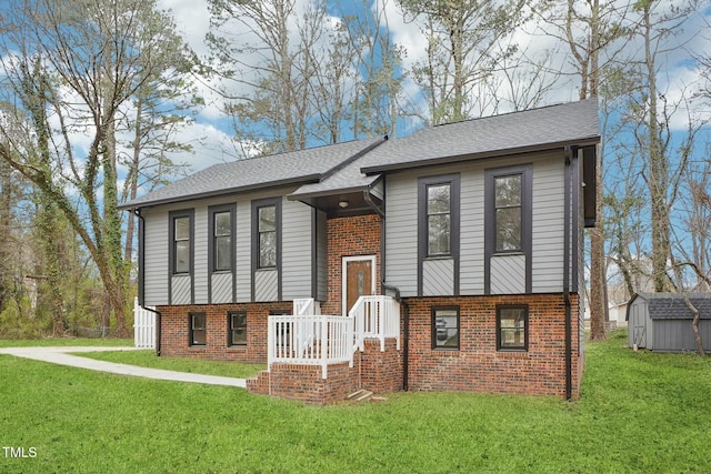 split foyer home with brick siding, a shingled roof, a front yard, an outdoor structure, and a storage unit