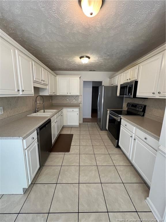 kitchen with light tile patterned floors, stainless steel appliances, a sink, white cabinetry, and light countertops