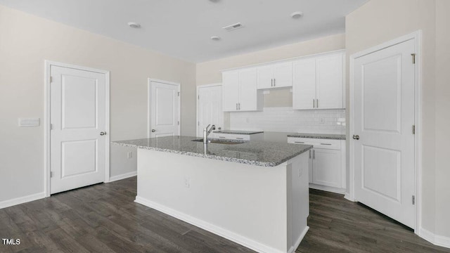 kitchen with dark wood-type flooring, an island with sink, a sink, and white cabinets