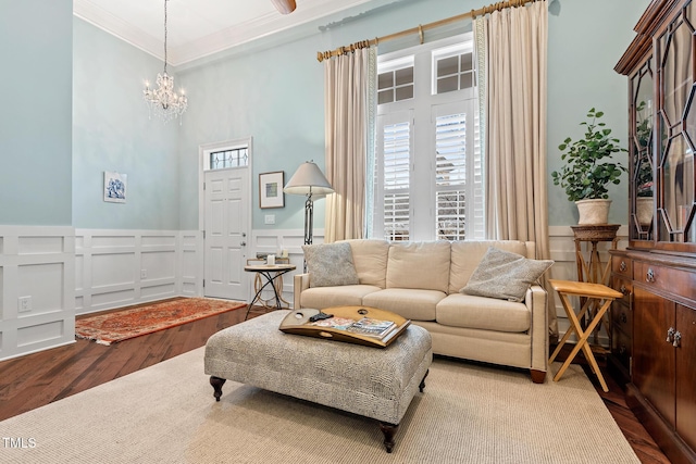 living room featuring an inviting chandelier, hardwood / wood-style floors, ornamental molding, and a healthy amount of sunlight