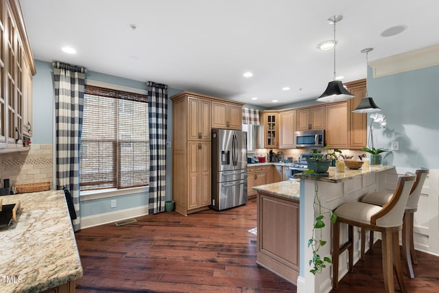 kitchen featuring a breakfast bar, pendant lighting, light stone counters, kitchen peninsula, and stainless steel appliances