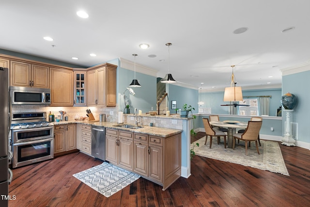 kitchen with sink, hanging light fixtures, stainless steel appliances, light stone counters, and tasteful backsplash