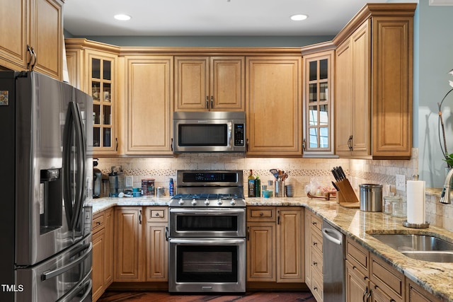 kitchen featuring light stone counters, stainless steel appliances, sink, and decorative backsplash