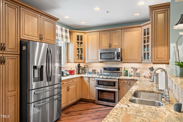 kitchen featuring sink, backsplash, light stone countertops, and appliances with stainless steel finishes