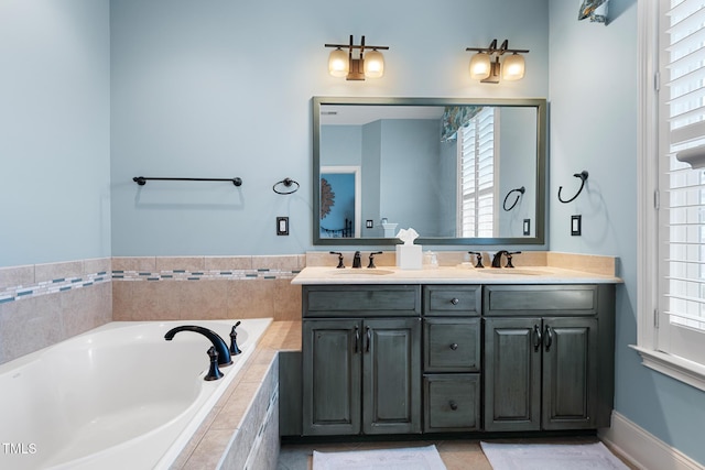 bathroom featuring vanity, tiled tub, and a healthy amount of sunlight