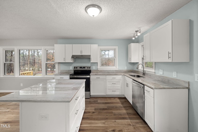 kitchen with sink, appliances with stainless steel finishes, a center island, light stone counters, and white cabinets