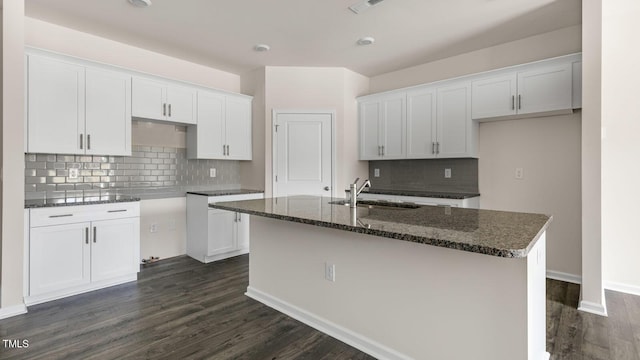 kitchen featuring dark wood finished floors, white cabinets, a sink, and a kitchen island with sink