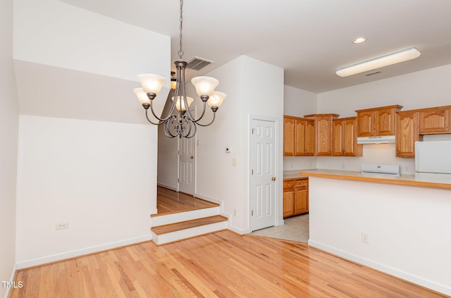 kitchen with decorative light fixtures, white refrigerator, a notable chandelier, light hardwood / wood-style floors, and stove