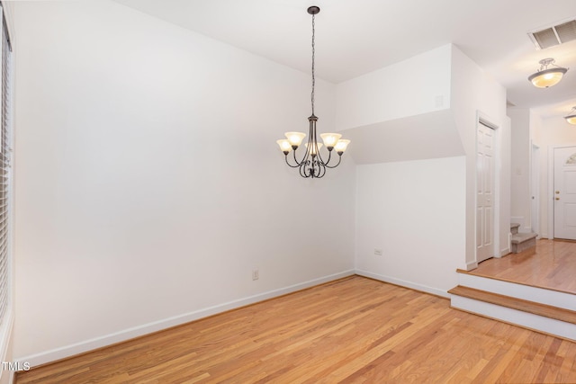 spare room featuring an inviting chandelier, lofted ceiling, and light hardwood / wood-style floors