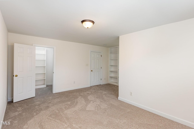 unfurnished bedroom with a spacious closet and light carpet