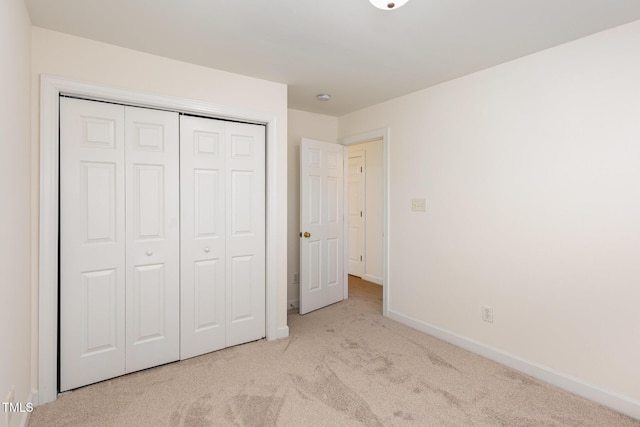 unfurnished bedroom with light colored carpet and a closet