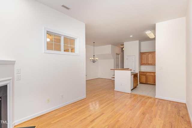 unfurnished living room with an inviting chandelier and light hardwood / wood-style flooring