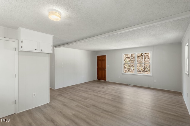 unfurnished room featuring light hardwood / wood-style flooring and a textured ceiling
