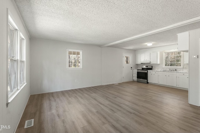 unfurnished living room with light hardwood / wood-style floors, sink, and a textured ceiling