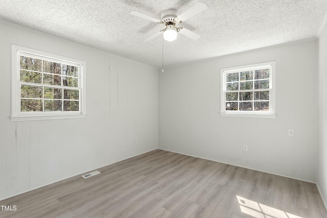 spare room with light wood-type flooring, a textured ceiling, and ceiling fan