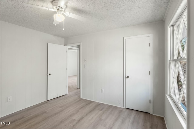 unfurnished bedroom featuring a textured ceiling, ceiling fan, and light hardwood / wood-style flooring