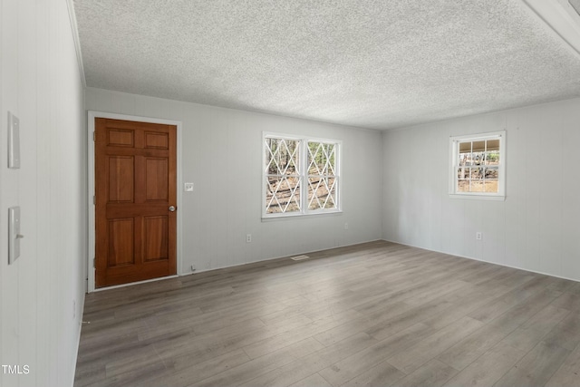 unfurnished room featuring light wood-type flooring and a textured ceiling