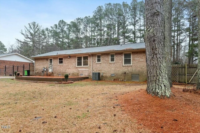 rear view of property with central AC and a lawn