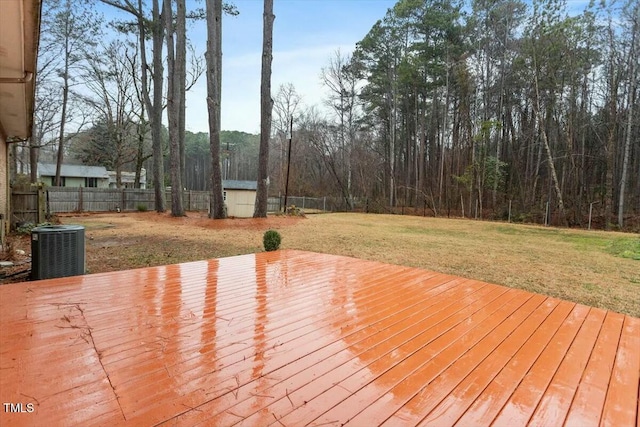 wooden deck with a storage shed, a yard, and central AC