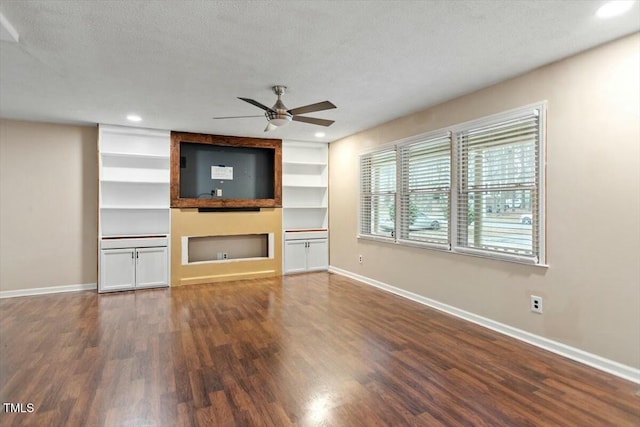 unfurnished living room featuring built in features, ceiling fan, a fireplace, a textured ceiling, and dark hardwood / wood-style flooring